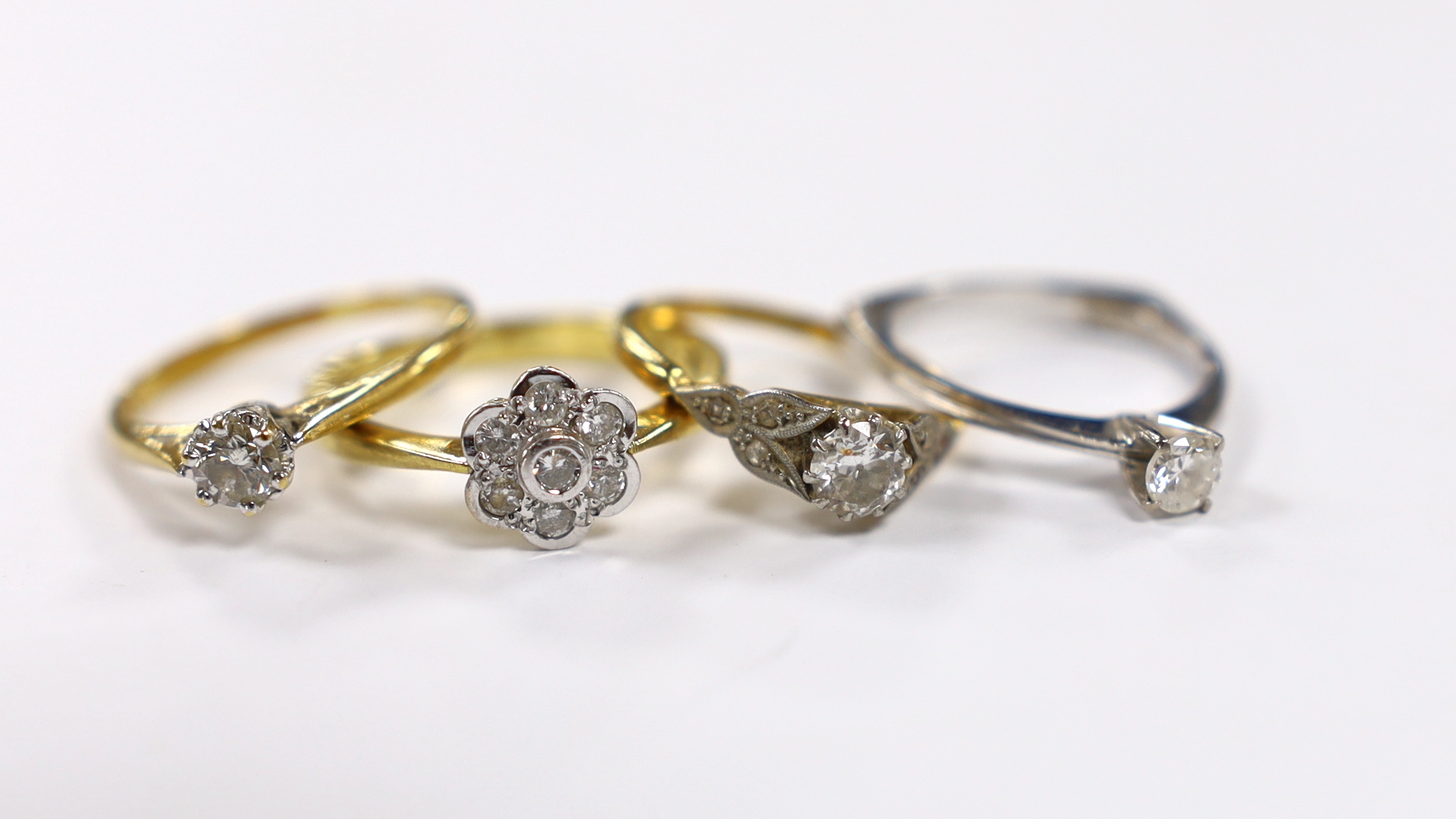 Three assorted 18ct and solitaire diamond rings and an 18ct gold and diamond set flower head ring, gross weight 10.8 grams.